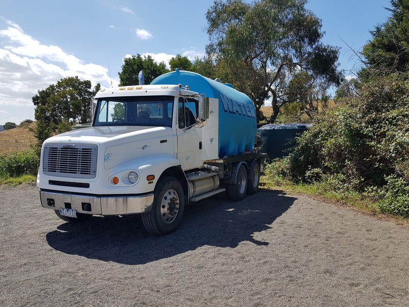 Water cartage truck delivering water to a rainwater tank in the Hills